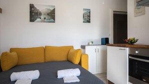 A modern hotel room with a large bed, a sofa, a kitchenette, and two landscape paintings on the wall. - Beau séjour 15 by Interhome (Ovronnaz)