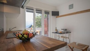 A modern kitchen with a wooden countertop, a fruit bowl, and a dining area with a table and chairs. - Beau séjour 15 by Interhome (Ovronnaz)