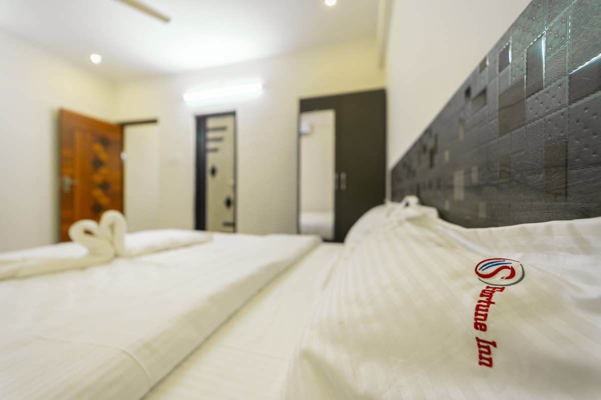 A hotel room with a bed, a wooden door, and a wall with a textured pattern.