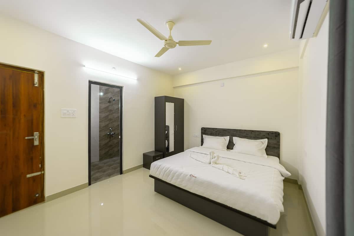 A modern bedroom with a large bed, a ceiling fan, a wardrobe, and a marble shower area.