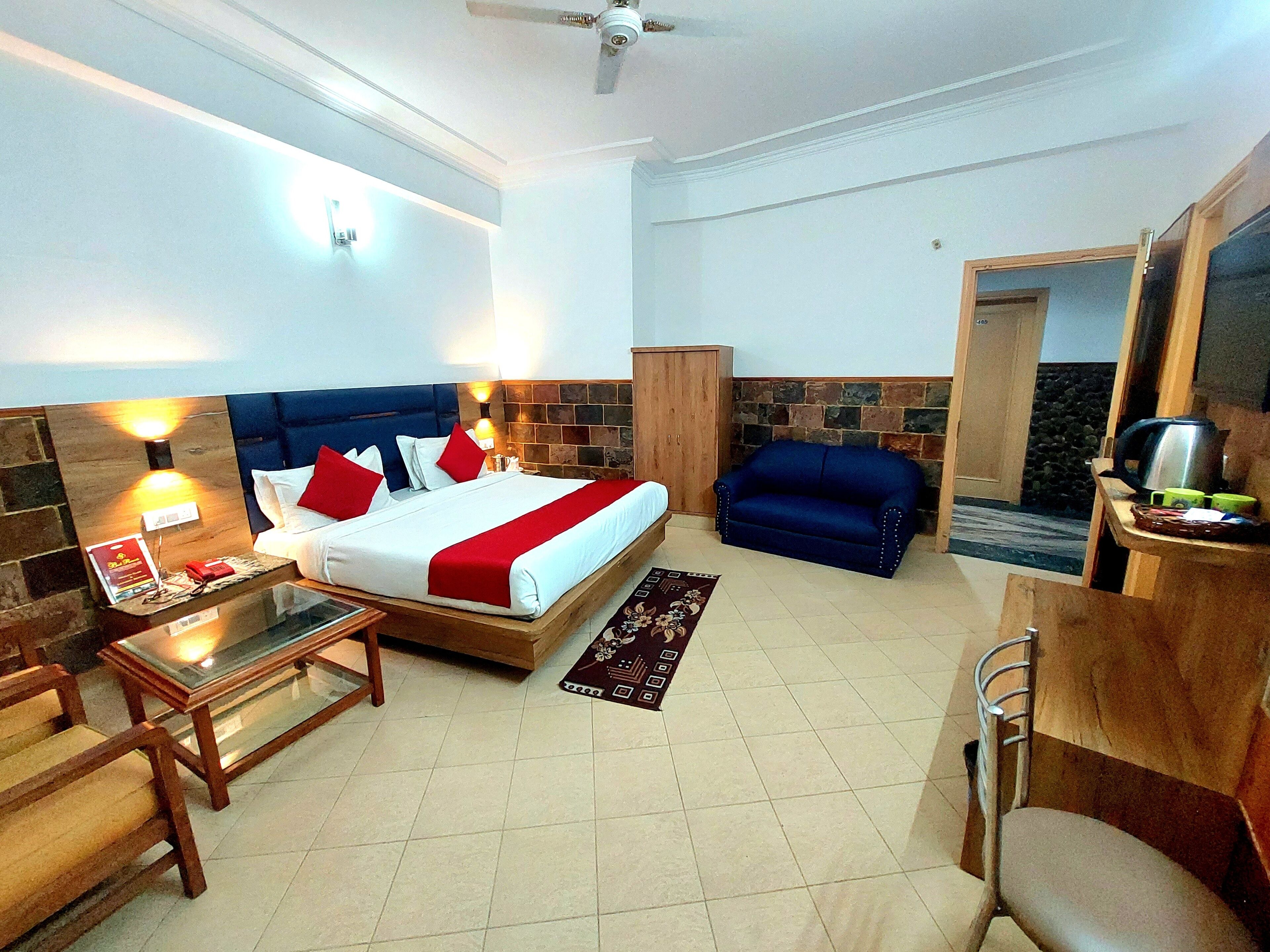 Una habitación de hotel con cama, escritorio, sillón, sofá y kitchenette.
