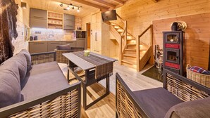 A cozy wooden cabin interior with a dining area, sofa, and kitchen.