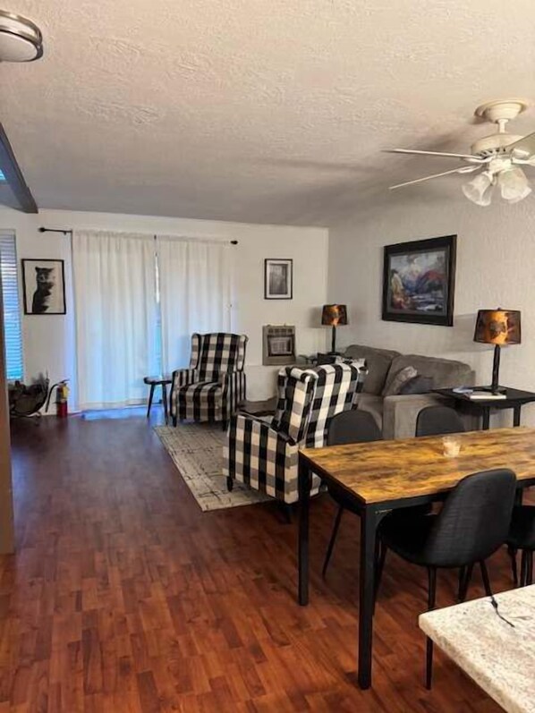 Una sala de estar con sofá, sillones, una mesa de comedor y un ventilador de techo.