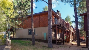 A rustic wooden building with a balcony, surrounded by trees. - Latitude Adjustment by Velo (Angel Fire)