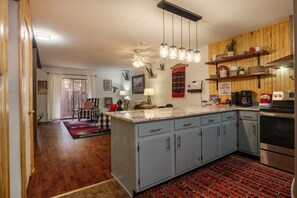 Una cocina con armarios azules, encimera de madera y lámpara colgante.
