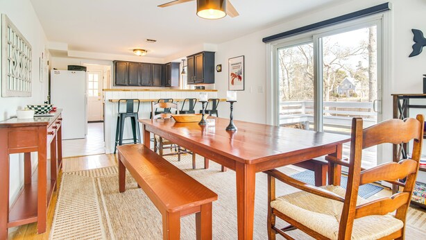 A modern kitchen with a wooden dining table, chairs, and a ceiling fan. - 1 Mi to Sand! Mid-Cape Chatham w/ Furnished Deck (Chatham)
