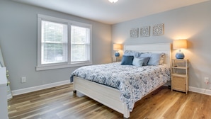 A bedroom with a bed, two bedside lamps, a window with blinds, and a ceiling light.