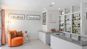 Eine moderne Küche mit weißen Schränken, einer Bar mit Flaschenregalen und einer Sitzecke mit einer Couch und einem Couchtisch.