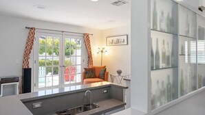 Eine moderne Küche mit integriertem Spülbecken, einem Essbereich mit Tisch und Stühlen sowie durch große Glastüren erreichbarem Außenbereich.