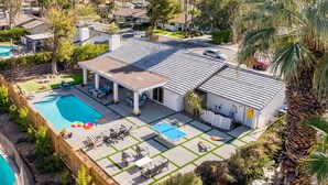 Ein Wohnhaus mit Swimmingpool, Terrassenbereich mit Liegestühlen und einer überdachten Sitzgelegenheit im Freien.