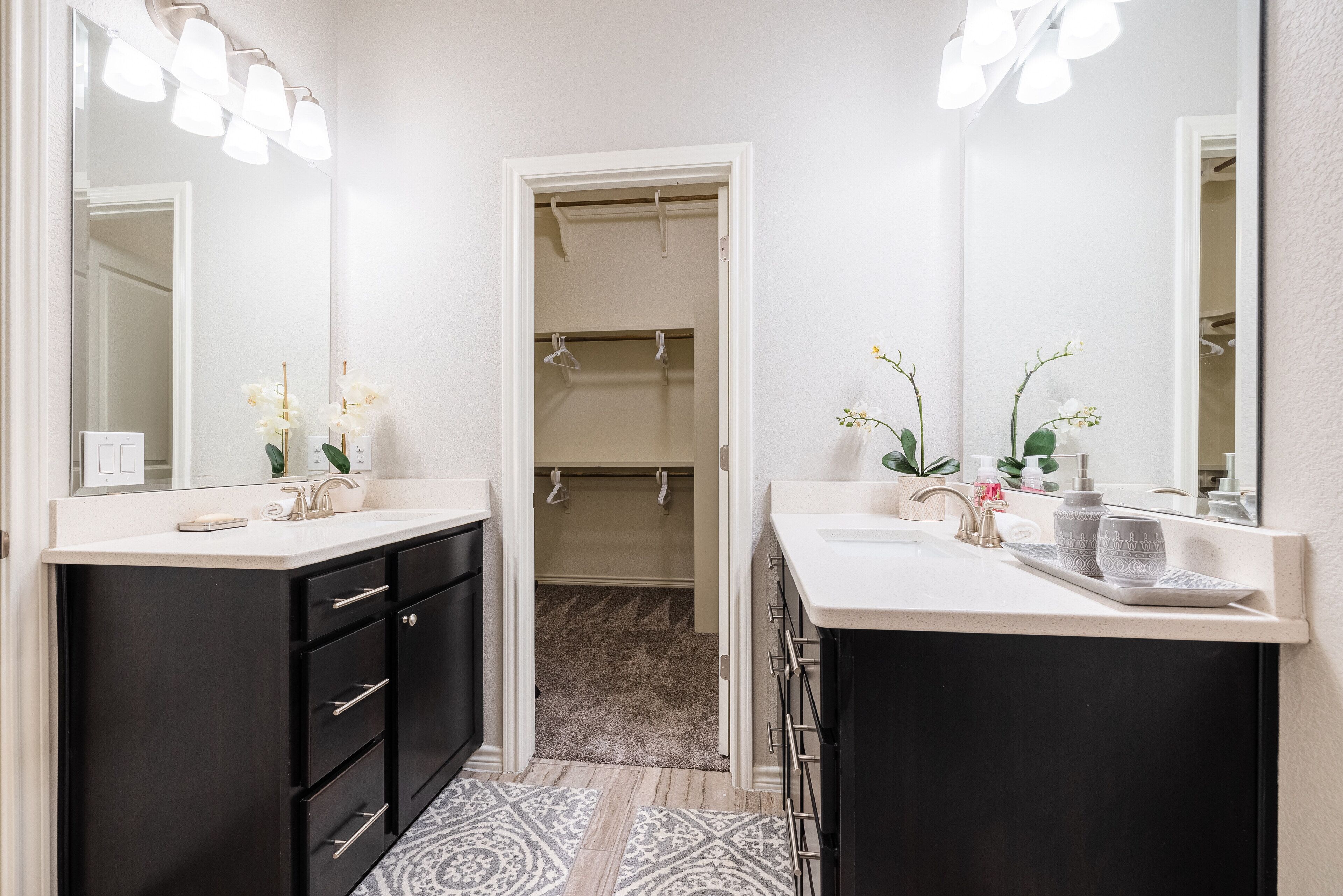 Une salle de bain avec deux lavabos, des meubles noirs et un dressing.