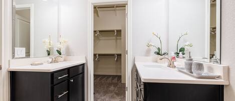 Une salle de bain avec deux lavabos, des meubles noirs et un dressing.