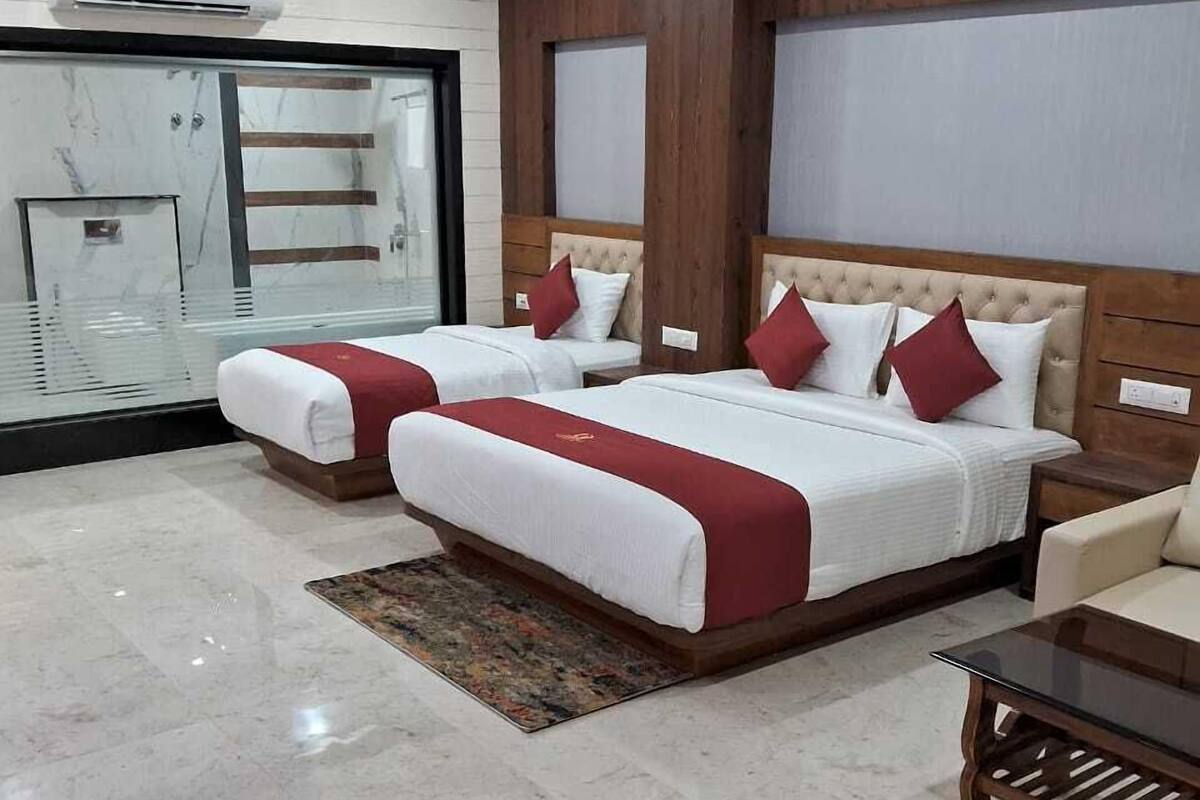 A hotel room with two beds, marble flooring, a ceiling fan, and a large window.