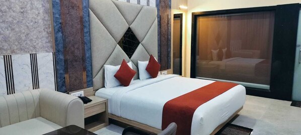 A hotel room with a bed, a nightstand, a chair, and a large window.