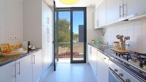 A modern kitchen with white cabinets, a gas stove, and a dining area with breakfast items. - Precious time by Interhome (Tavira)