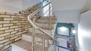 Un escalier moderne avec des rampes en métal et des murs en pierre.