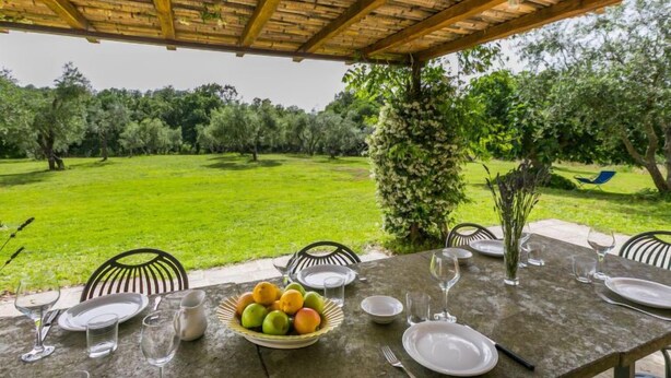 An outdoor dining area with a table set for four, surrounded by chairs, and a view of a lush garden. - Il Piccione by Interhome (Pitigliano)
