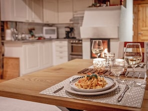 A dining table set with a plate of pasta, glasses, and a candle. - Rukanlumous 3 by Interhome (Kuusamo)