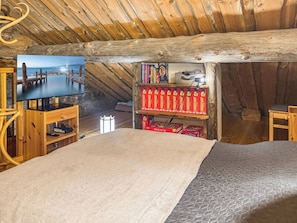 A cozy attic bedroom with a TV, wooden shelves, and a bed. - Rukanlumous 3 by Interhome (Kuusamo)