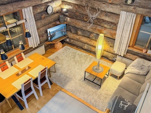 A cozy log cabin interior with a dining area, a sofa, a TV, and a decorative antler piece. - Rukanlumous 3 by Interhome (Kuusamo)