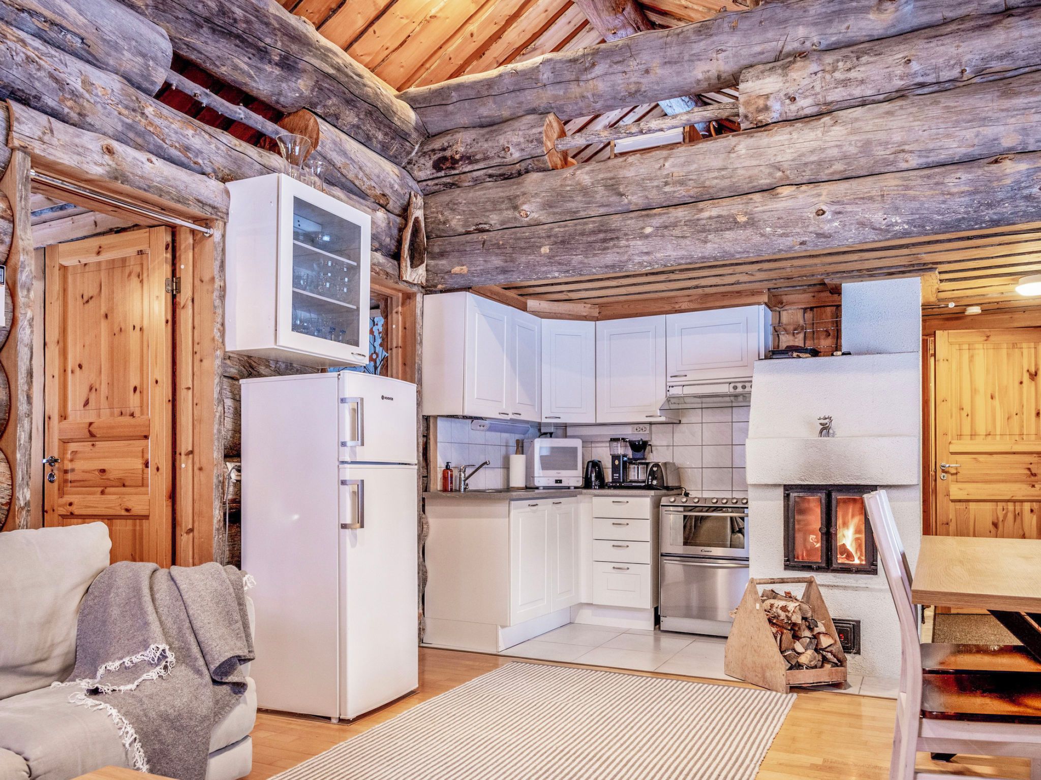 Interior rústico de una cabaña con kitchenette, gabinetes de madera, un refrigerador, estufa y chimenea.