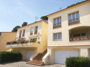 Un immeuble résidentiel à plusieurs étages, doté d’un escalier, de balcons et d’un garage.