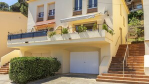 Een woonhuis met twee verdiepingen, een witte gevel, een balkon en een garage.
