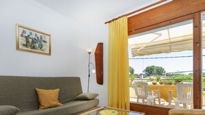 Een woonkamer met een bank, een glazen salontafel en een eethoek met stoelen en een tafel.