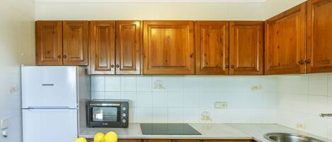 Una cocina con armarios de madera, un refrigerador Liebherr, un horno tostador y un cuenco de fruta en la encimera.