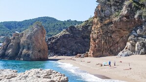 A beach with rocky formations and clear blue water.