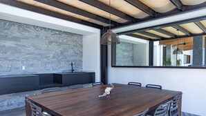 Un espace de salle à manger moderne avec une table en bois et des chaises en métal, un luminaire suspendu et un mur en pierre.
