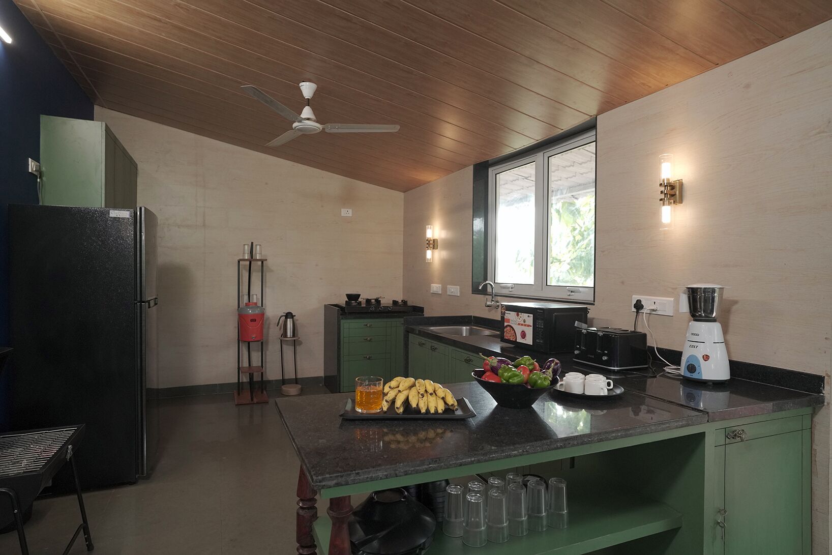 Una cocina compacta con una isla central, un refrigerador, una cafetera y una licuadora.