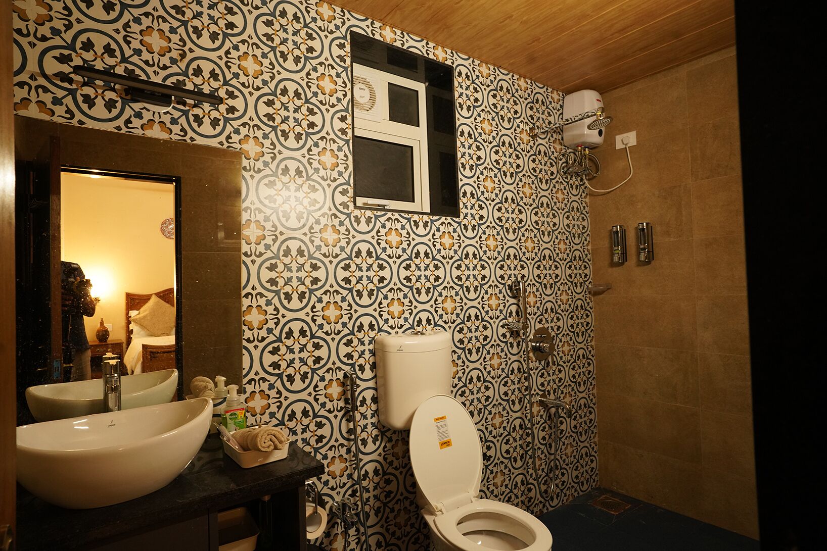 A bathroom with a patterned tile wall, a sink, a toilet, and a shower.