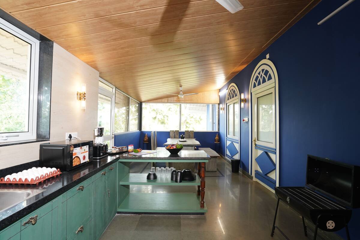 A kitchen with a wooden ceiling, a central island, and a blue accent wall.
