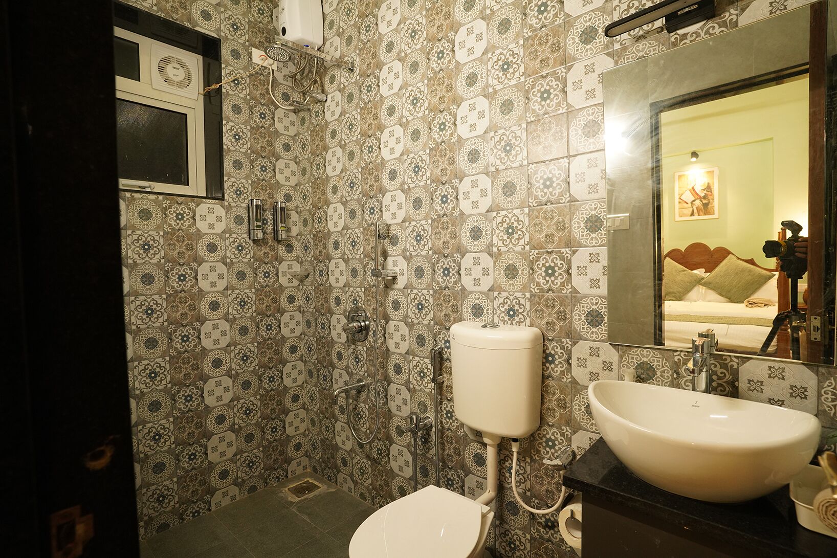 Une salle de bain avec des carreaux décorés, des toilettes, un lavabo et une douche.