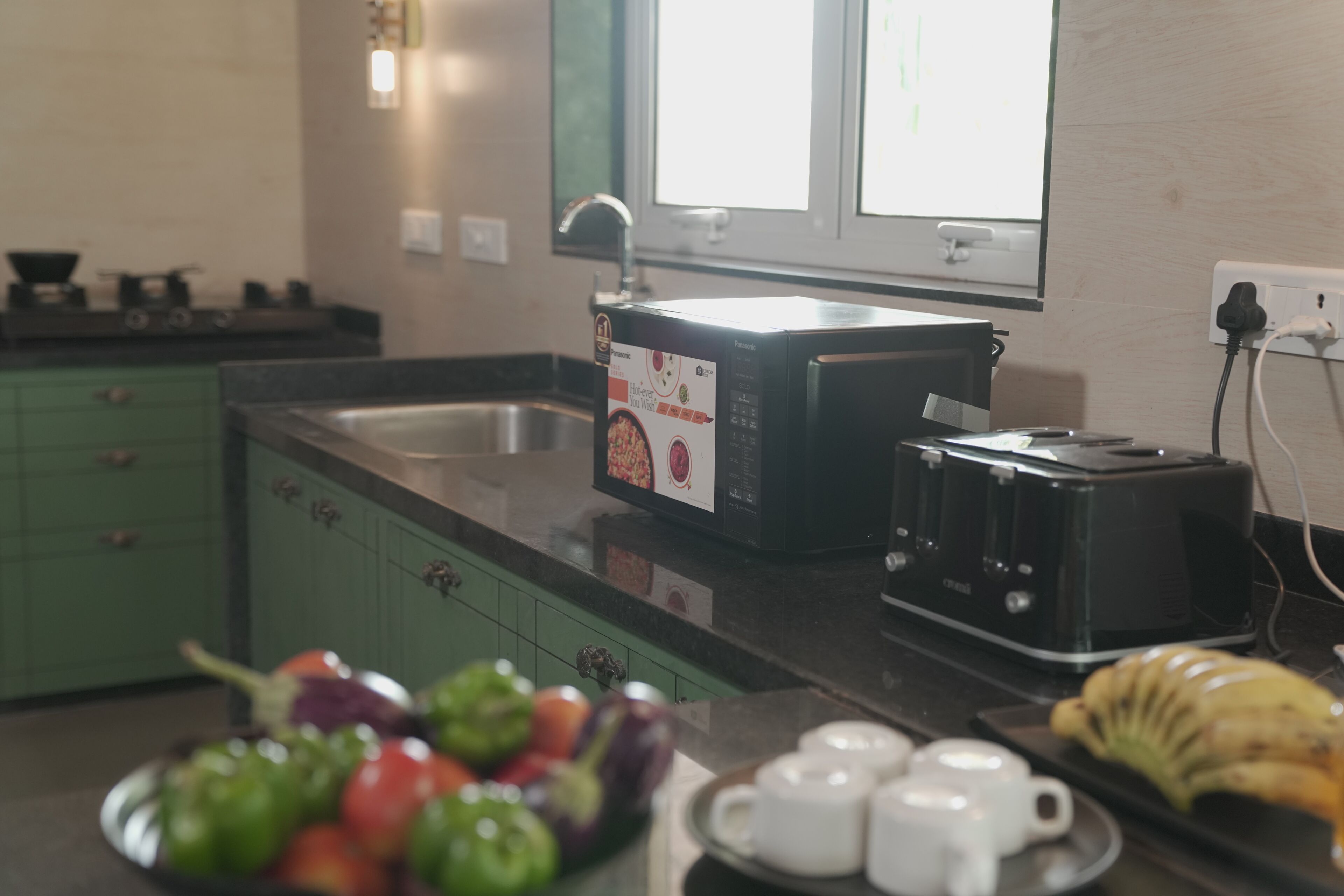A kitchen with a microwave, toaster, and a bowl of fruit.