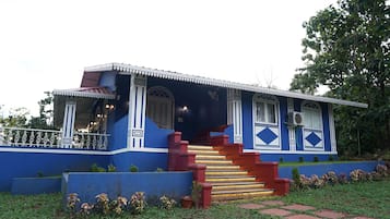 Un edificio de dos pisos con fachada azul, escalera roja y barandilla de balcón blanca.