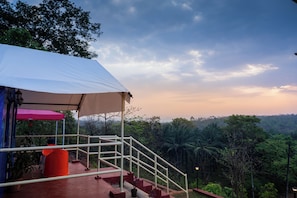 Un espacio al aire libre cubierto con una escalera que conduce a un nivel superior, rodeado de abundante vegetación y un cielo despejado.