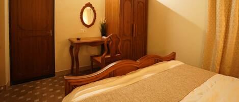 A bedroom with a wooden bed, a desk with a mirror, and a wardrobe.