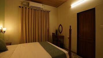 A bedroom with a bed, an air conditioner, a wooden door, and a wall-mounted mirror.