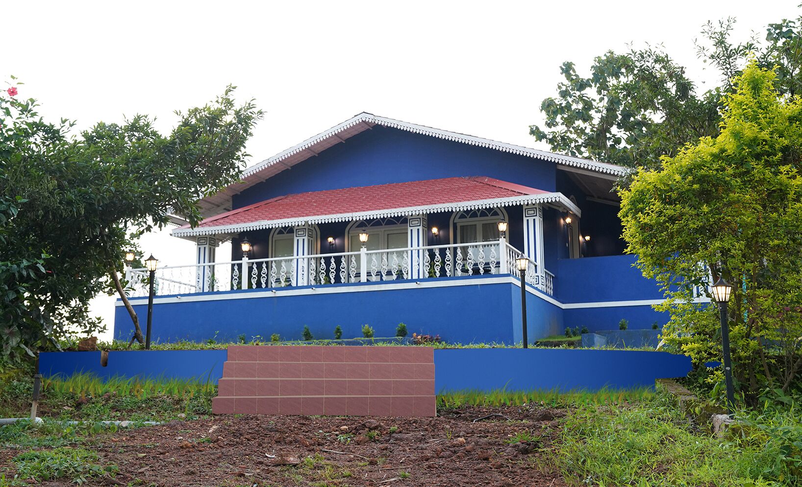 Un edificio azul con techo rojo, barandillas de balcón blancas y base de ladrillo.
