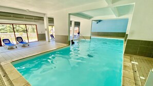 An indoor swimming pool with clear water, tiled floor, and blue lounge chairs. - T2 vue Montagne, Accès Direct aux Pistes, Avec Piscine (Vars)