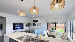 Een moderne keuken met een groot eiland, roestvrijstalen apparatuur en hangende lampen.