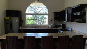 A kitchen with a large island, dark cabinets, a microwave, and a stove. - Villa Hermosa Spacious Close Town And Sosua Beach (Sosúa)