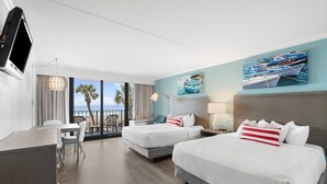 A hotel room with two beds, a desk, and a view of the ocean. - Oceanfront Bliss: Oceanfront Room 4th Floor (Myrtle Beach)