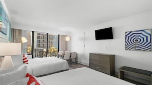 Hotellihuone, jossa on kaksi sänkyä, työpöytä, tuoli, televisio ja parveke, jolta on näkymä.