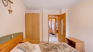 A bedroom with a wooden bed, a fur throw, a wardrobe, and a bench. - Apartment 'Lovin Winter' with Mountain View, Private Balcony and Wi-Fi (Livigno)