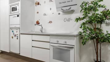 Une cuisine avec des appareils électroménagers blancs, un évier et une plante en pot.