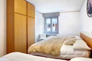 A bedroom with a bed, a wooden wardrobe, a window, and a radiator. - Apartment 'Lovin Summer' with Mountain View, Private Balcony and Wi-Fi (Livigno)