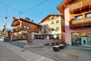 A street view with a wooden building with balconies, a shop with a sign 'NeroGiardini,' and a store with a sign 'Jolly J.' - Apartment 'Lovin Summer' with Mountain View, Private Balcony and Wi-Fi (Livigno)
